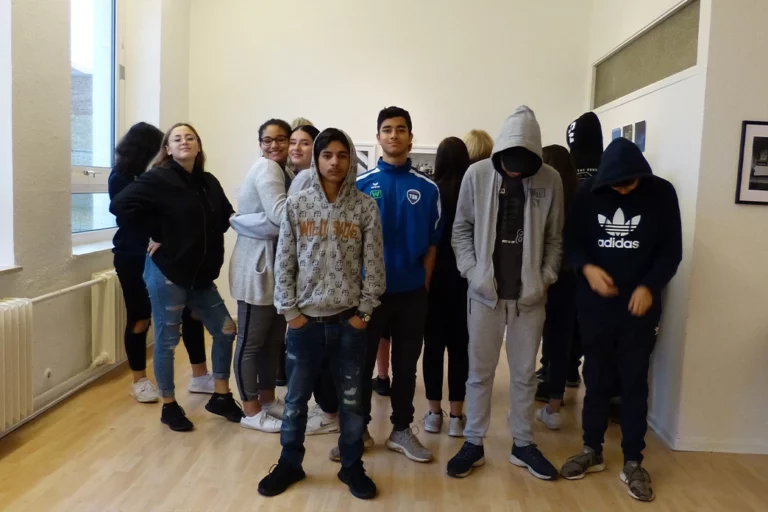 Gruppe von Schülerinnen im Stehen, teilweise mit verdeckten Gesichtern.