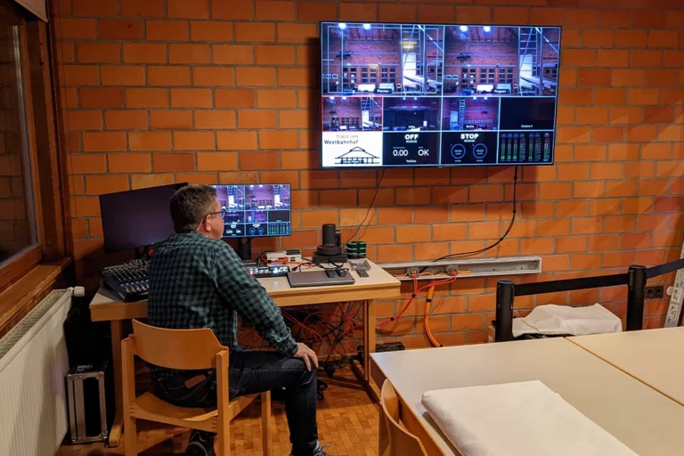 Mann sitzt vor Computer und großem Screen im digitalen Schnitt